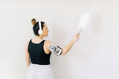 woman in black tank top and white skirt holding gray and black headphones
