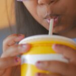 A young girl drinking from a yellow cup