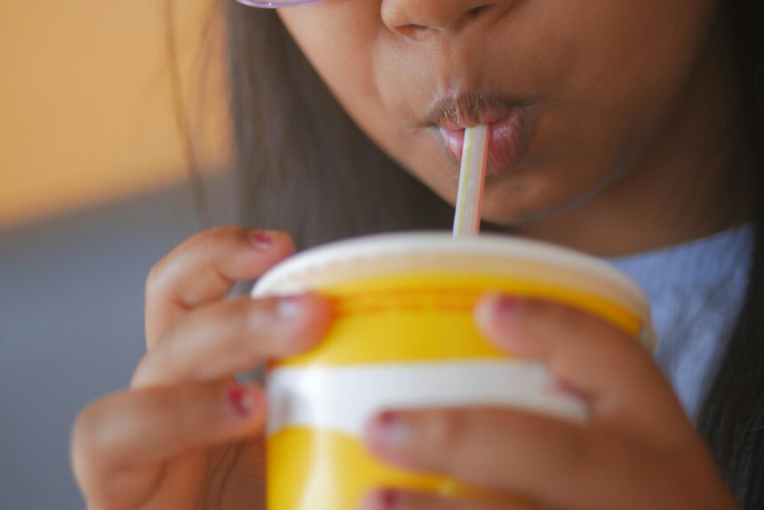 A young girl drinking from a yellow cup